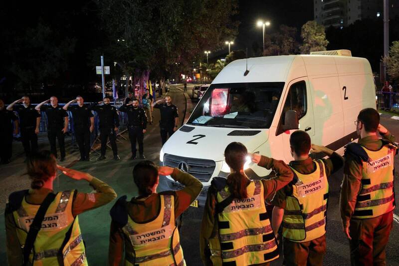 10月15日，以色列特拉维夫，运送遗体的车队抵达法医中心，以色列军警列队敬礼。（路透）