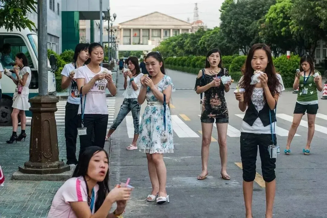早上上班前，电子厂的女工，买好早餐后站在路边上吃，然后上班。