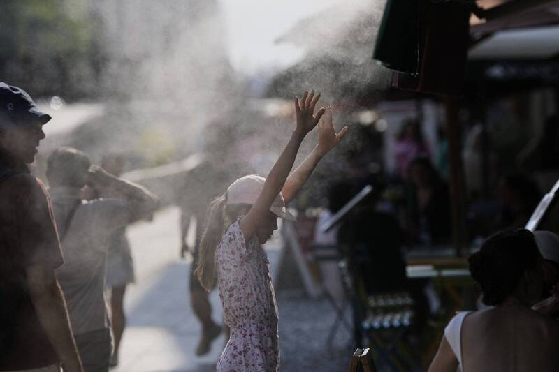 在义大利米兰纳维利区，一名儿童在一家餐厅外停下来，用雾化器降温。（美联社）