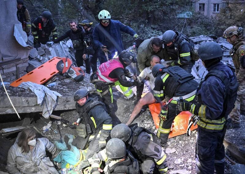 救难人员10日在遭俄国攻击的乌克兰札波罗热的废墟中，把受困民众从瓦砾堆中抬出来。（路透）